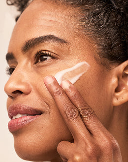 Target Close-up of woman applying cream to cheek for targeted skincare treatment