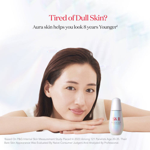 Woman resting chin on folded hands with SK-II GenOptics Infinitaura Serum bottle placed beside the face on a soft gradient background