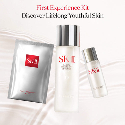 Hand holding SK-II Facial Treatment Essence bottle near face with liquid flowing around the bottle on a neutral background