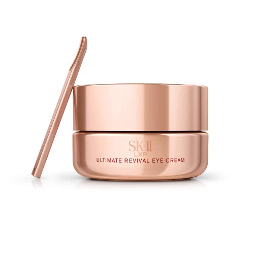 SK-II LXP Ultimate Revival Eye Cream bottle held in hand with golden liquid flowing over fingers on a neutral background