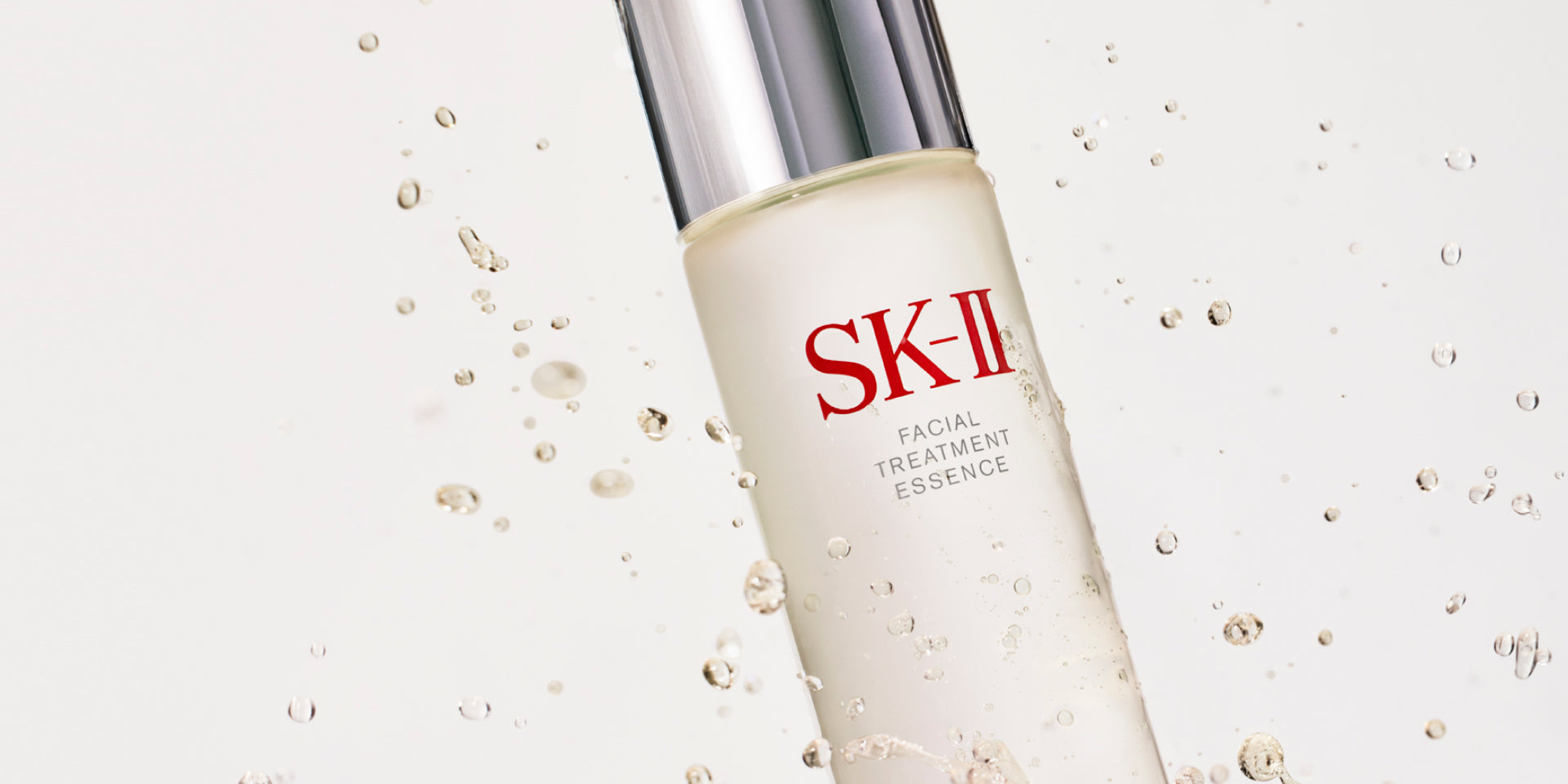 SK‑II Facial Treatment Essence bottle shown at an angle with liquid droplets against a light background