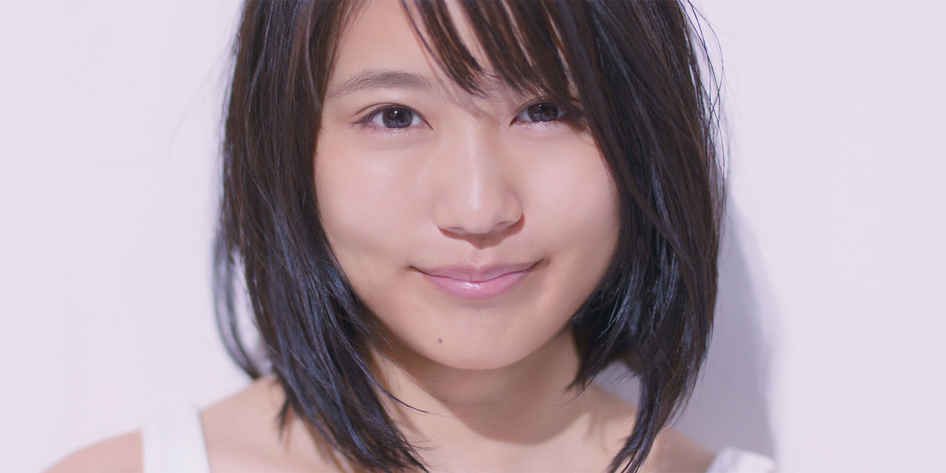 Close‑up facial image against a light background, showing even skin surface under soft, natural lighting