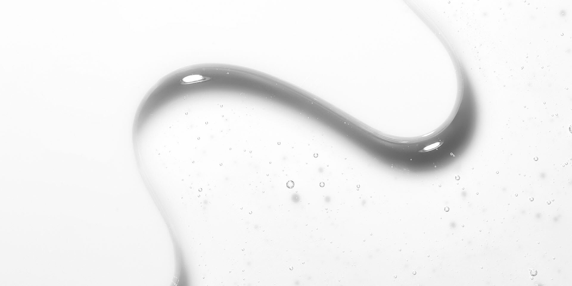 Clear skincare serum swipe with tiny bubbles on a white surface