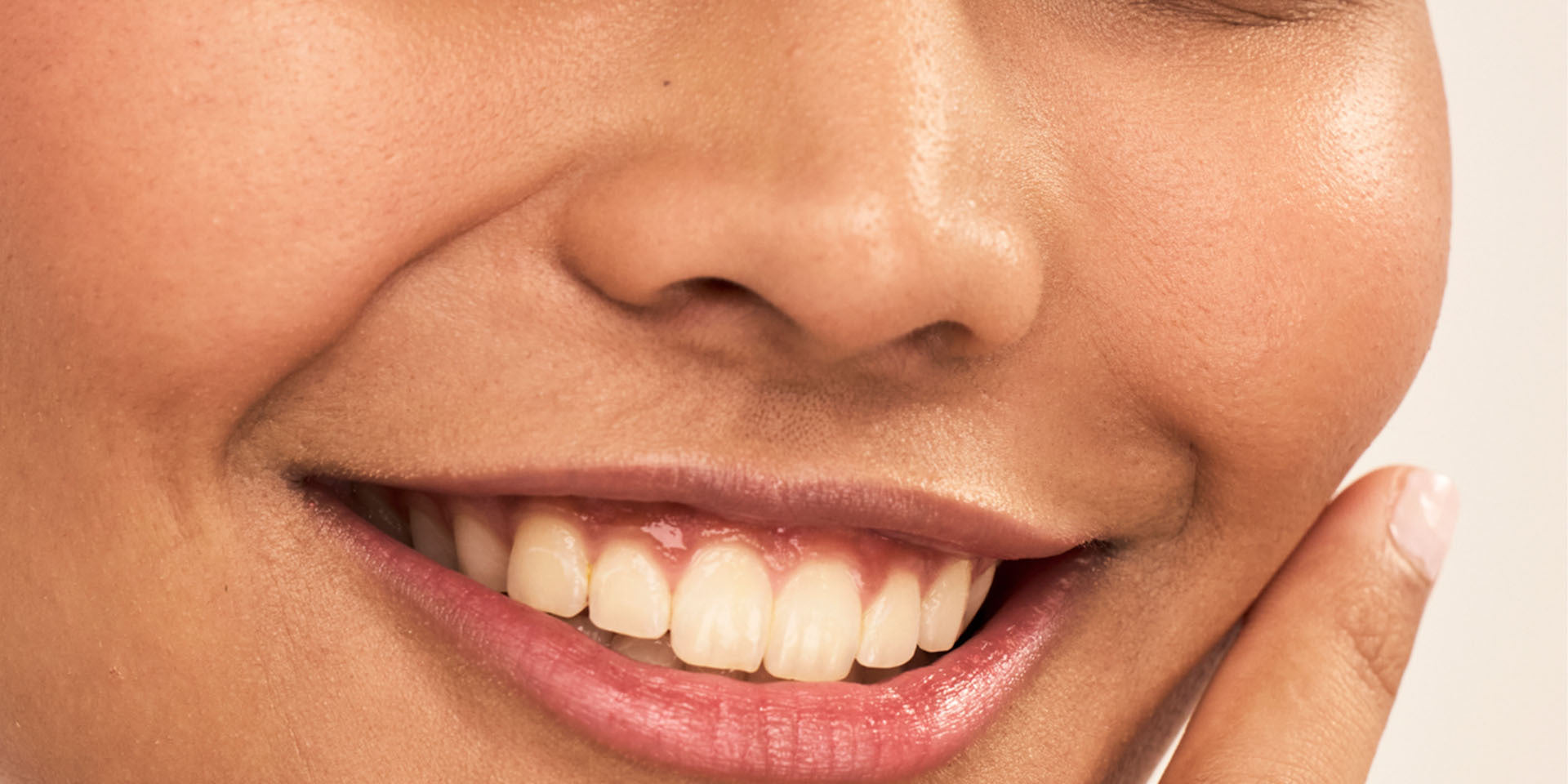 Close-up of lower face with hand touching cheek showing natural skin texture