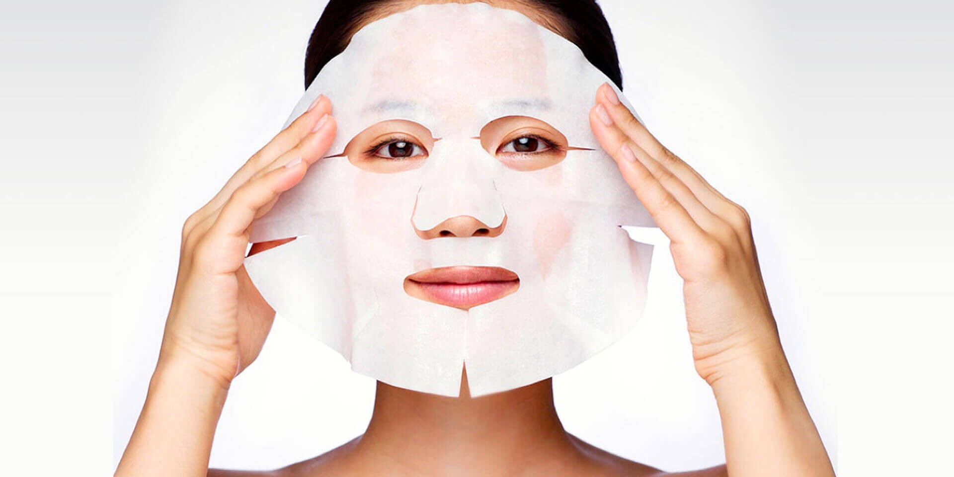 Woman applying SK-II face mask sheet onto her face with both hands
