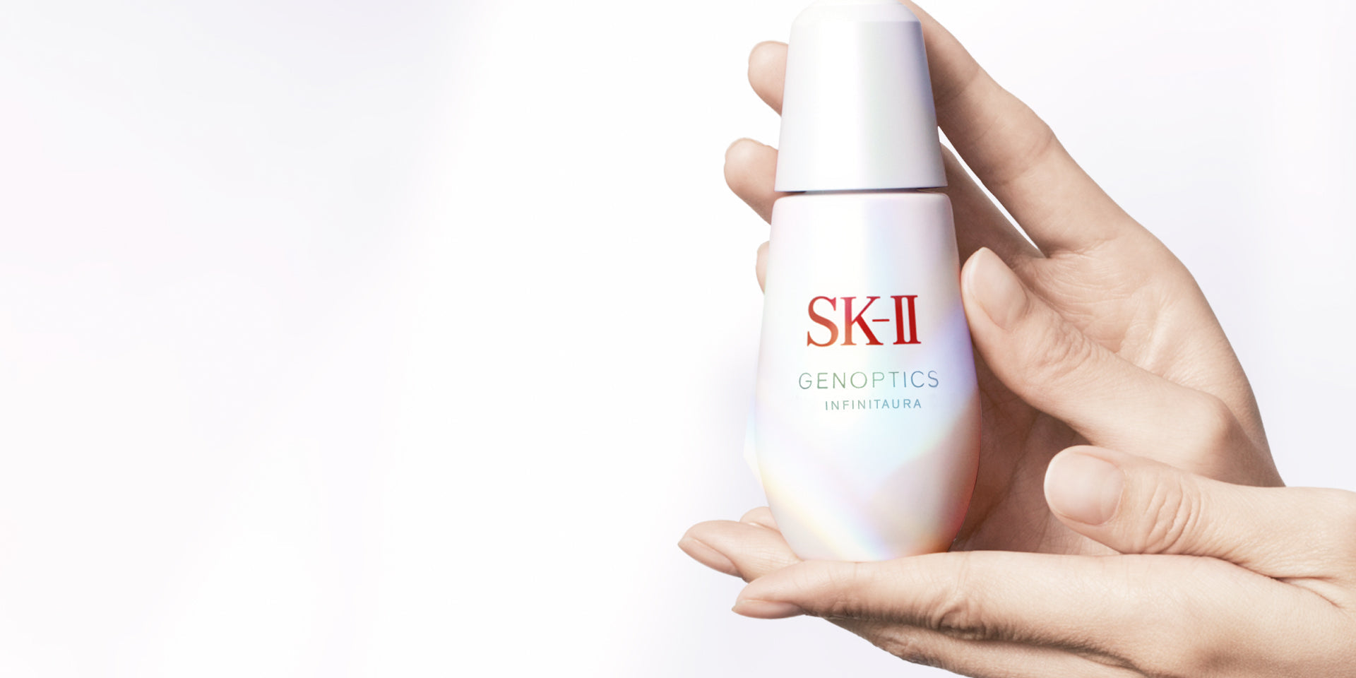 SK-II GenOptics serum bottle held in hands with a smooth gradient finish on a plain background