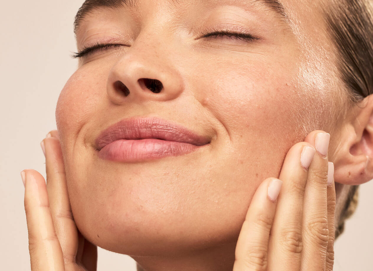Close-up of face with fingers along cheeks highlighting skin texture, associated with SK-II Facial Treatment Essence and PITERA