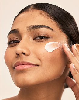 Close-up of woman applying cream to cheek during moisturizing skincare routine