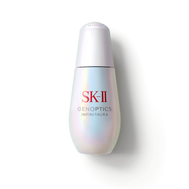 SK-II GenOptics Infinitaura Serum bottle with iridescent finish placed on a circular textured surface with soft light reflections