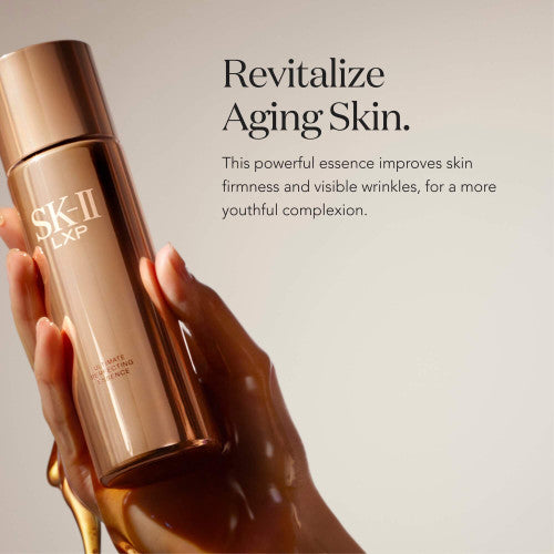 Hand holding SK-II LXP Ultimate Revival Essence bottle with golden liquid flowing over fingers against a neutral background