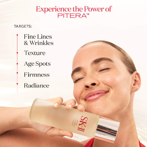 Hand holding SK-II Facial Treatment Essence bottle near face with smooth liquid visible on skin against a light background