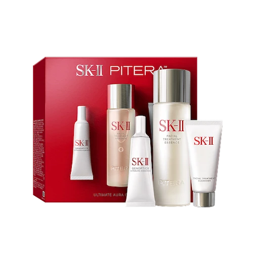 SK-II Pitera Ultimate Aura Essentials Kit products arranged with essence bottle and cleanser tube beside a red SK-II box on a light background