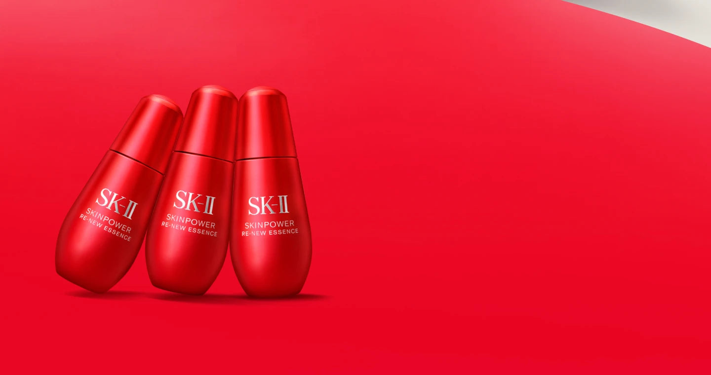 Three SK-II Skinpower Re-New Essence bottles in red packaging on red gradient background
 