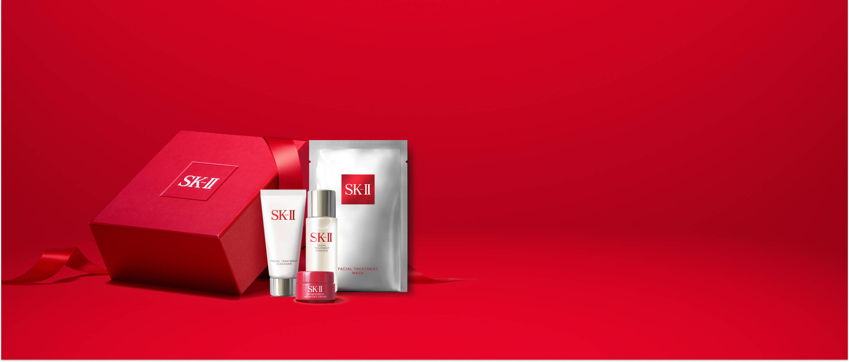 SK-II gift set with red box, cleanser, essence, cream, and mask on red background