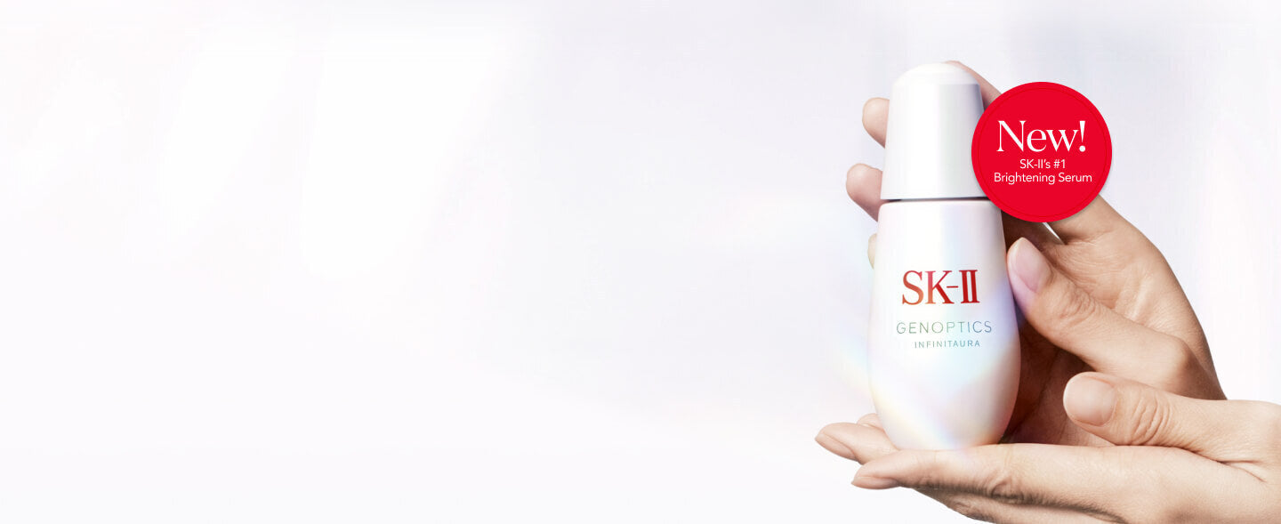 SK‑II GenOptics serum bottle held in two hands on light background with red circular label